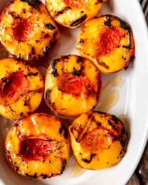 An image of a dish full of grilled peaches drizzled with honey.