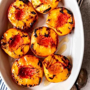 An image of a dish full of grilled peaches drizzled with honey.