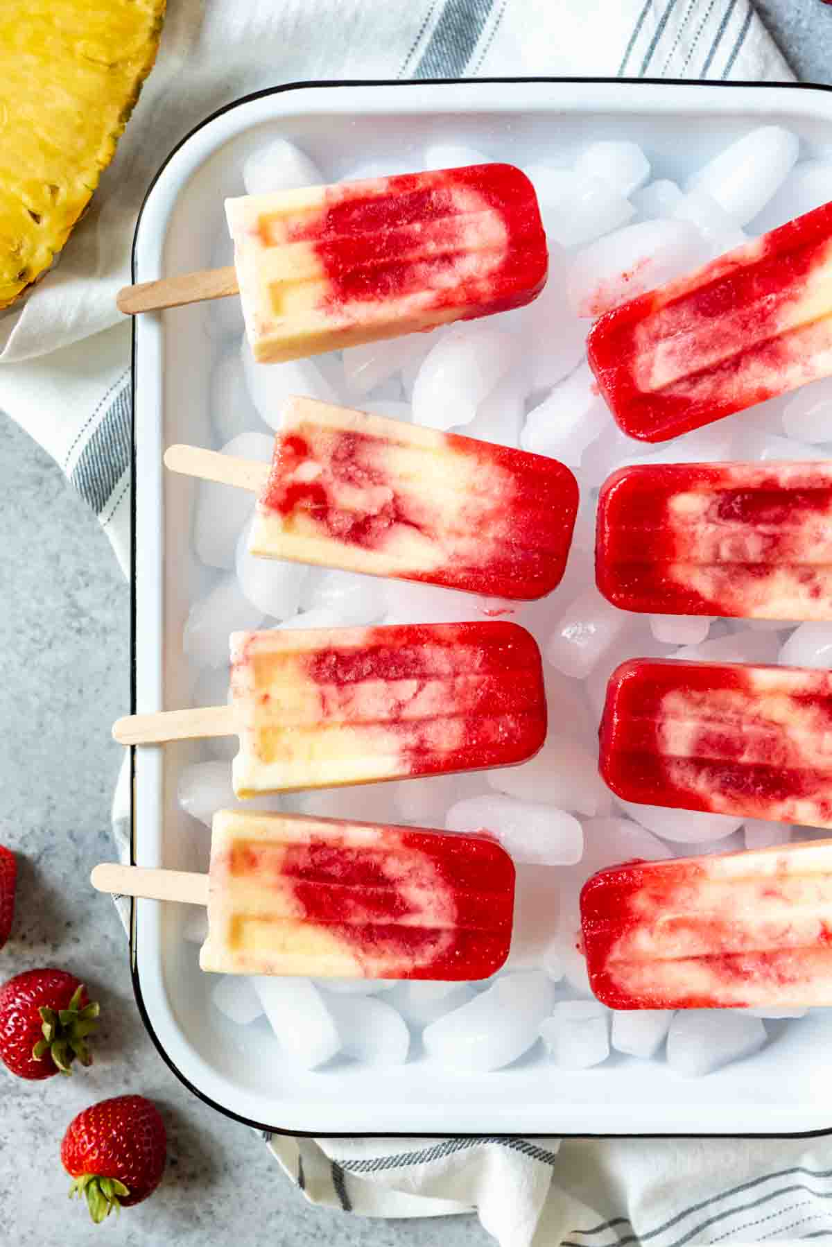 An image of a pan full of ice with homemade popsicles on top made with a swirl effect.