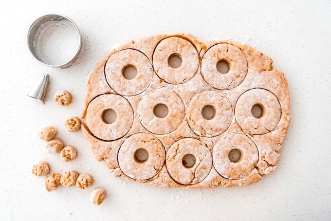An image of apple cider donut dough cut out into donut shapes using circle cutters.