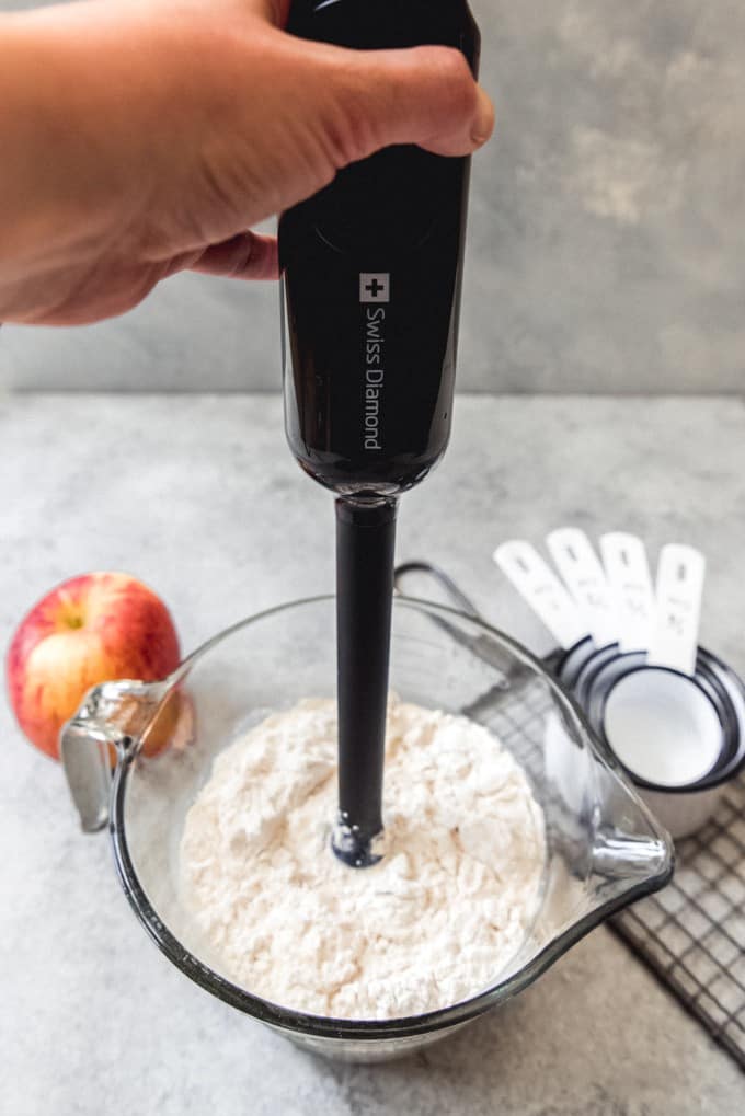 An image of an immersion blender in an easy german pancake batter to make German apple pancakes, otherwise known as apple dutch babies.