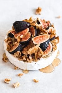 a wheel of baked brie covered in honey and figs and nuts
