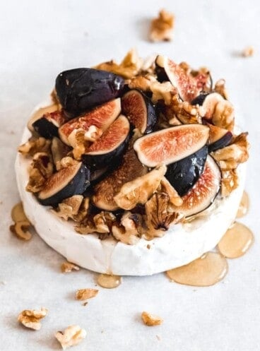 a wheel of baked brie covered in honey and figs and nuts