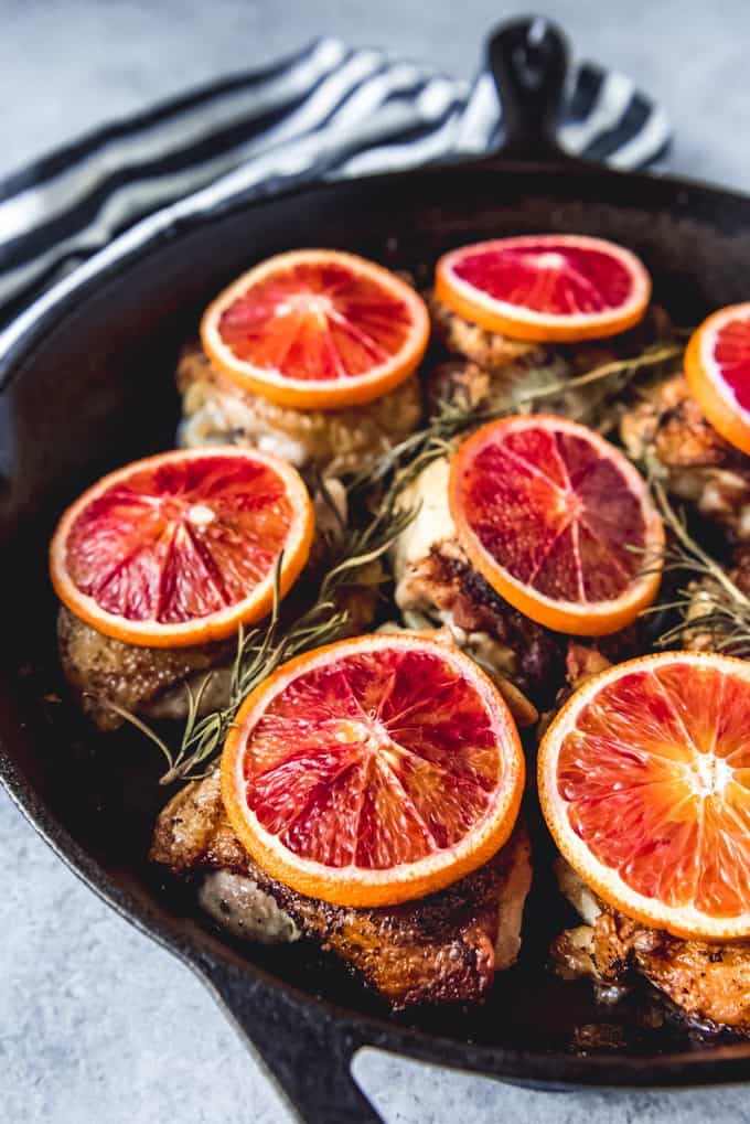 blood orange slices on top of cooked chicken thighs with fresh herbs
