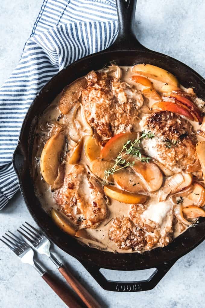 apple cider chicken in a skillet with apple slices