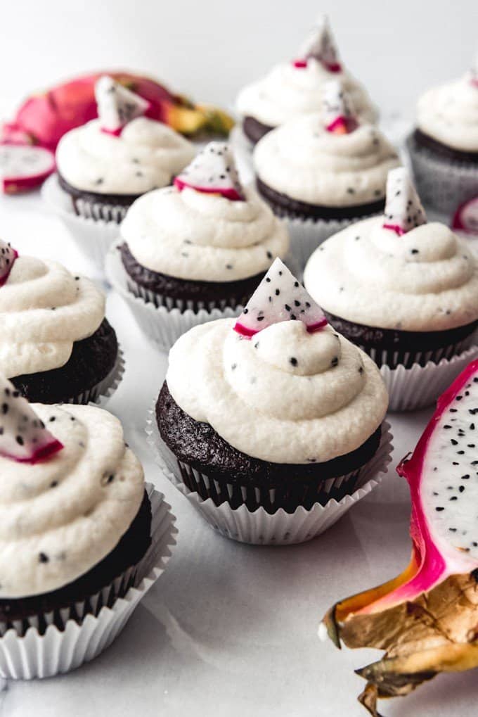An image of chocolate cupcakes with dragon fruit frosting, decorated with sliced dragon fruit.