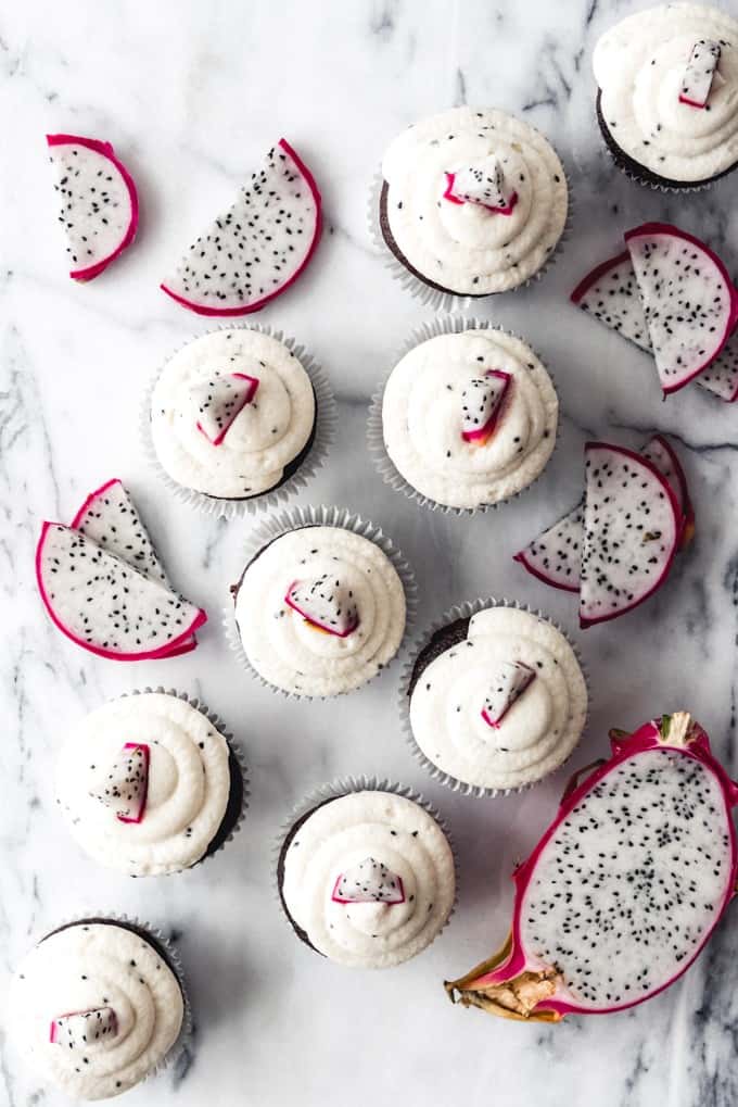 an aerial image of cupcakes with dragon fruit buttercream and sliced dragonfruit scattered between the cupcakes