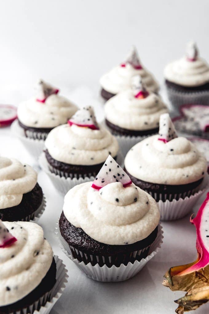 An image of chocolate cupcakes with dragon fruit frosting, decorated with sliced dragon fruit.