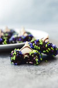 two chocolate blossom cookies with halloween sprinkles and white hershey kisses