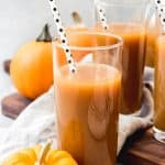 tall glasses filled with pumpkin juice with spotted strawbs inside and pumpkins scattered around