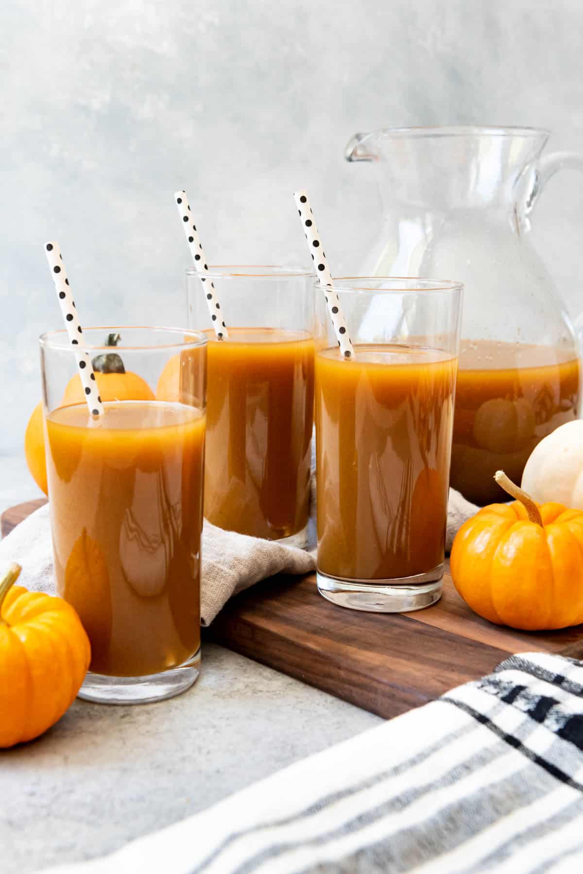 An image of glasses of chilled pumpkin juice made with apple cider, pumpkin puree, and pumpkin spice.