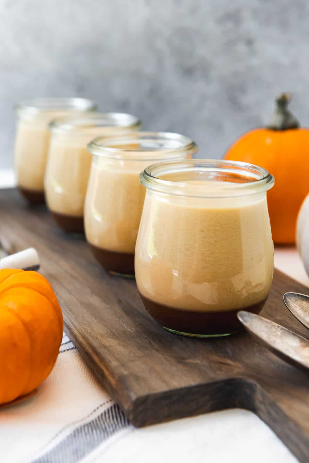 Rows of individual jars of pumpkin panna cotta with salted caramel sauce.