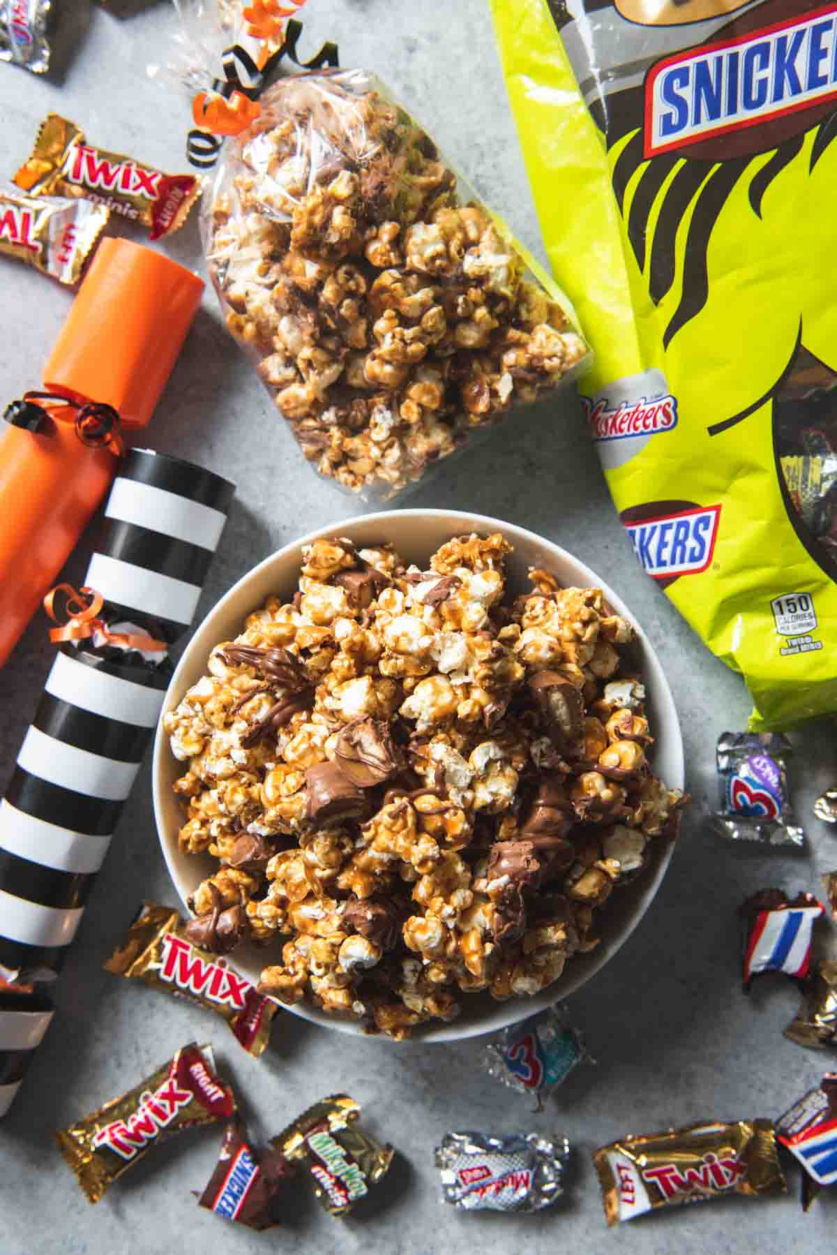 An overhead image of a bowl of Twix caramel corn surrounded by candy.