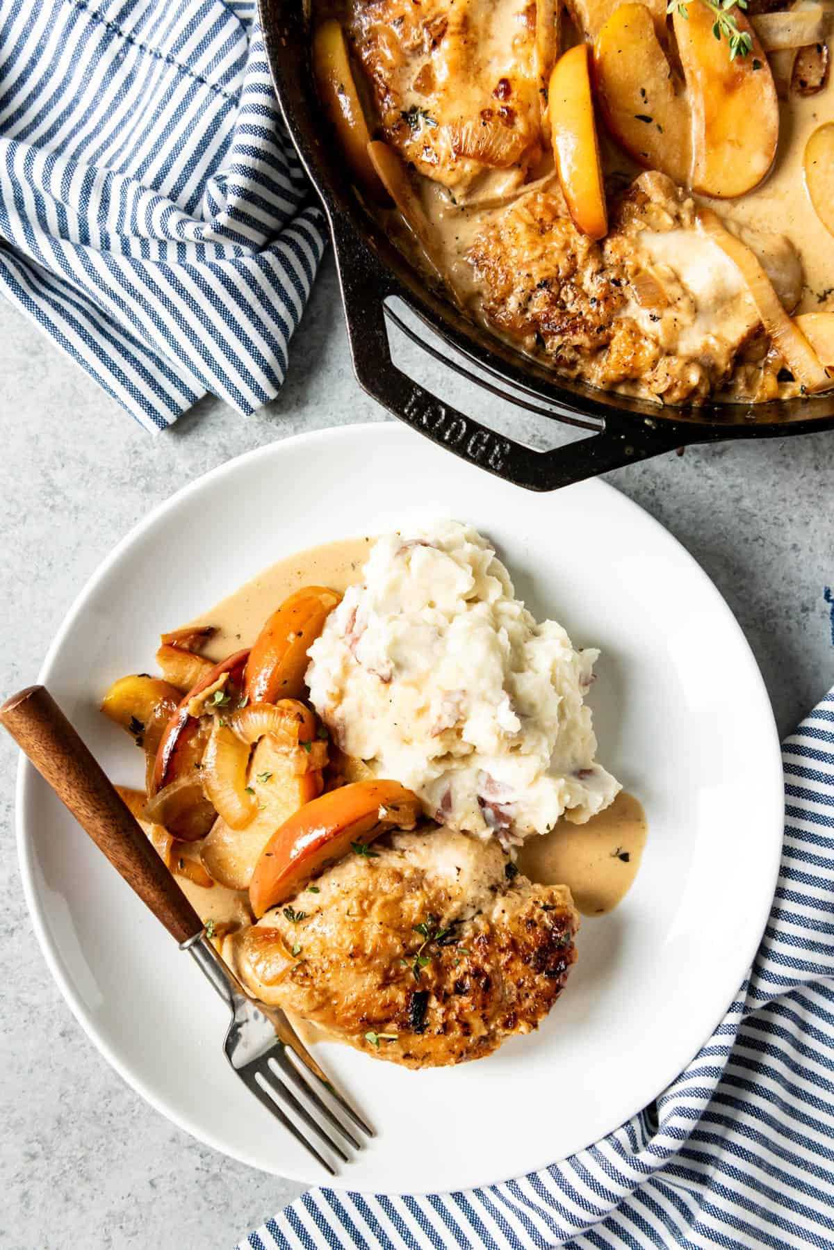 An image of a plate of creamy apple cider chicken skillet dinner with mashed potatoes on the side.