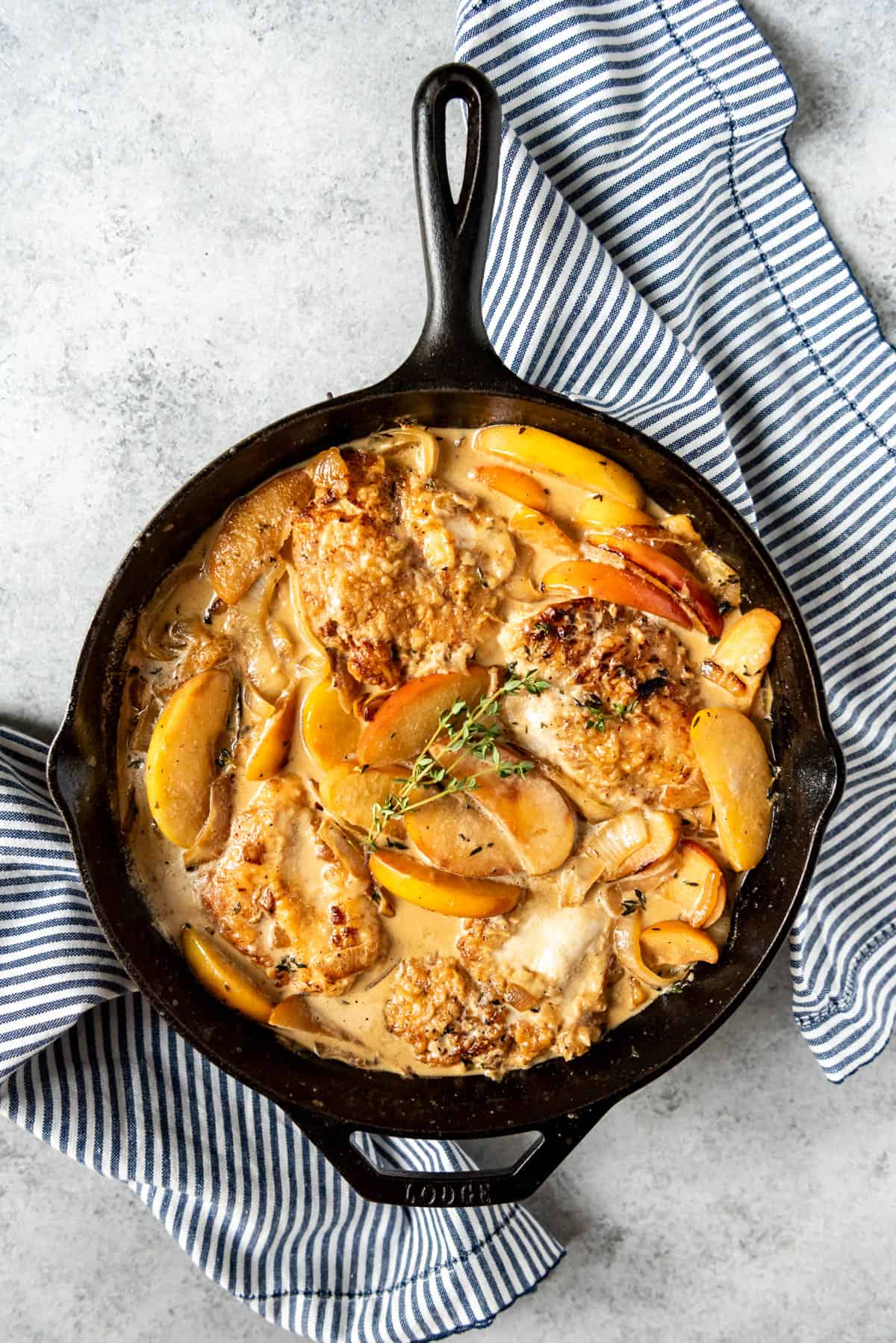 An image of a chicken fricassee with apples in a cast iron skillet makes the best fall dinner recipe!