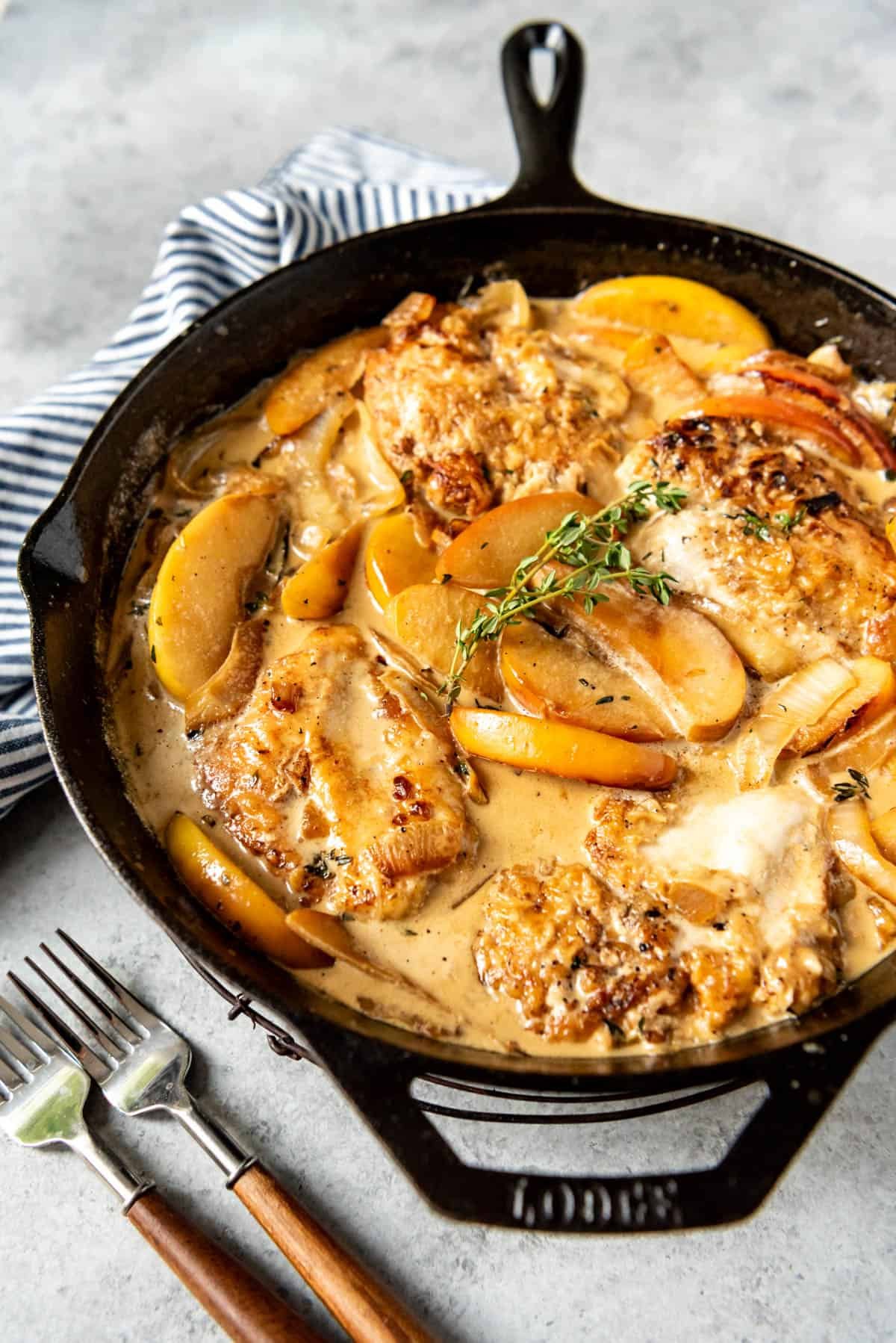 A side view of a skillet of creamy apple cider chicken.