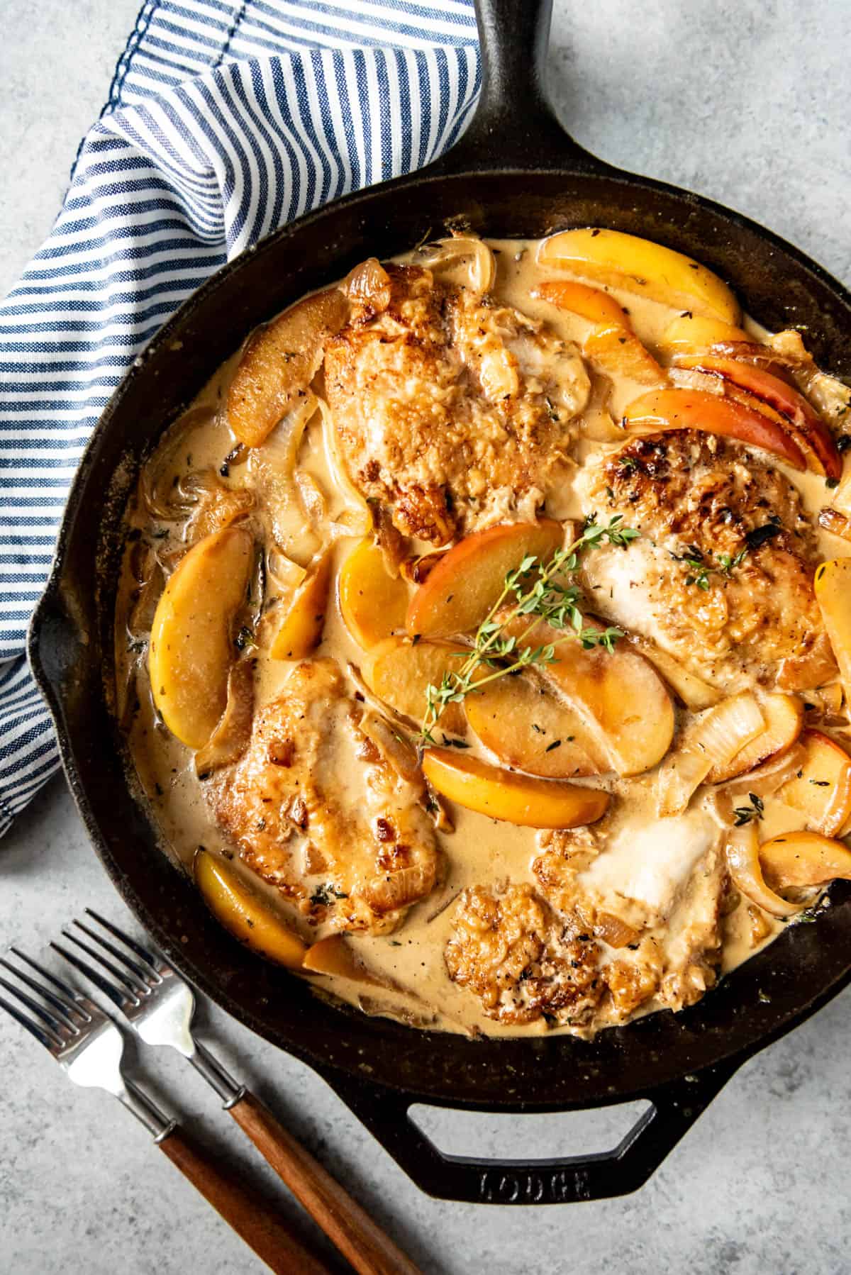 apple cider chicken in a skillet with apple slices