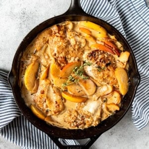 An image of a chicken fricassee with apples in a cast iron skillet makes the best fall dinner recipe!