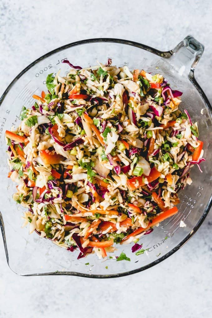 An image of an easy Asian slaw made with bagged coleslaw mix, along with lots of fresh vegetables and a peanut dressing.