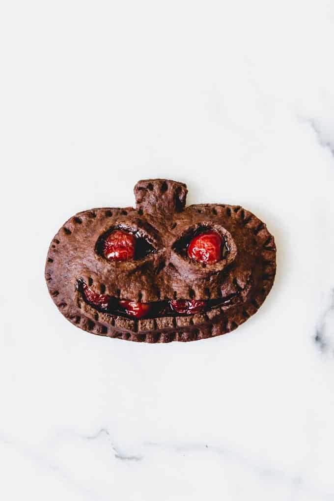An image of a grinning Jack-o-Lantern chocolate cherry hand pie for Halloween.
