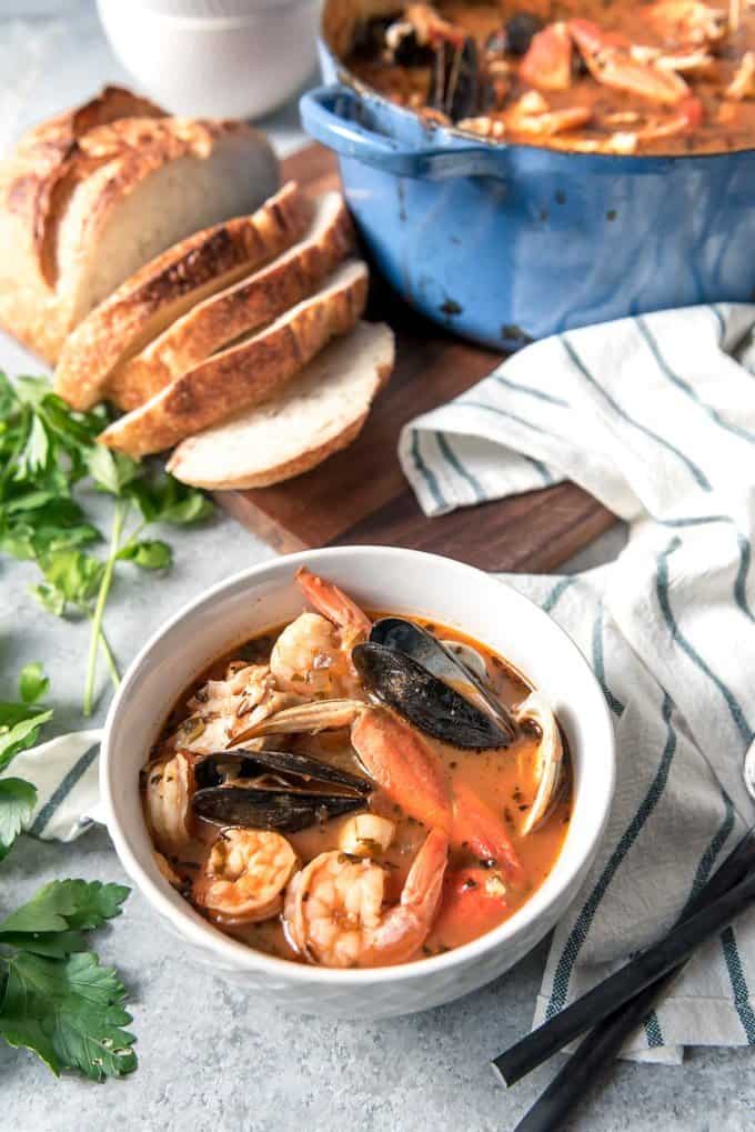 An image of a bowl of delicious San Francisco Cioppino made with fresh clams, mussels, shrimp, codfish, bay scallops, and Dungeness crab in a light tomato broth.