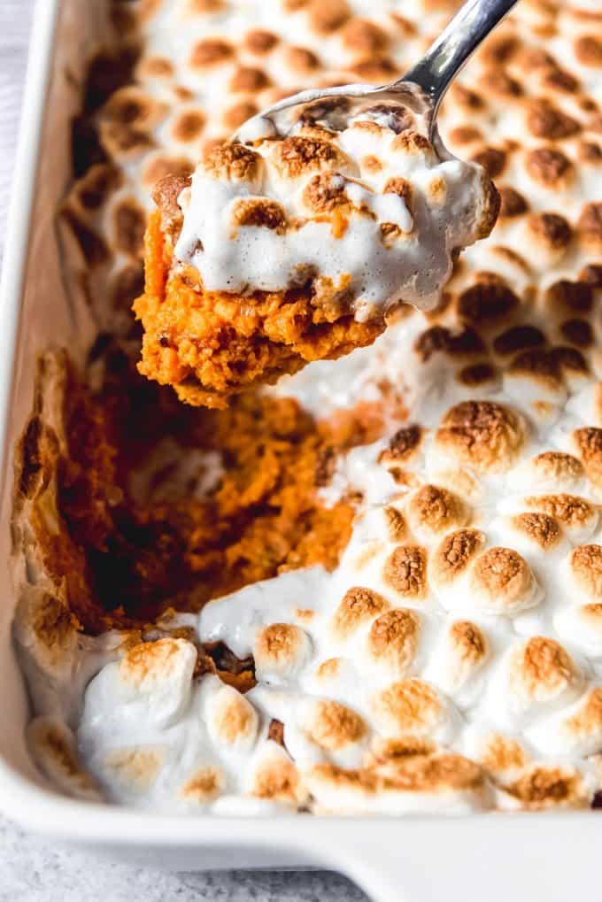 An image of a scoop of Thanksgiving sweet potato casserole with marshmallows toasted on top of a pecan streusel topping.