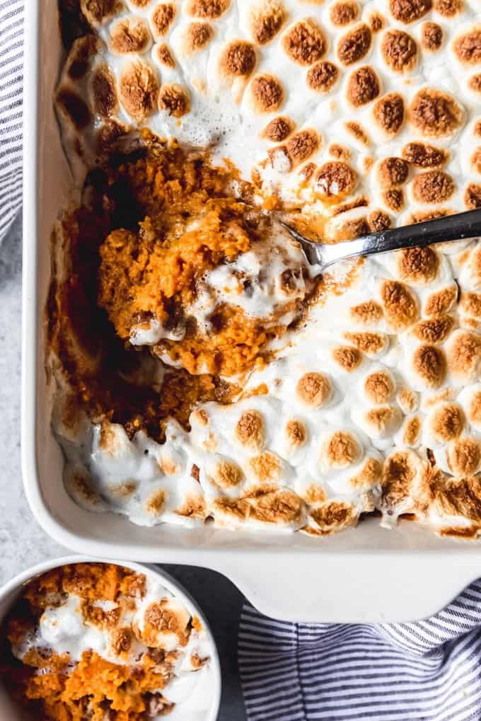 An image of a scoop of Thanksgiving sweet potato casserole with marshmallows toasted on top of a pecan streusel topping.