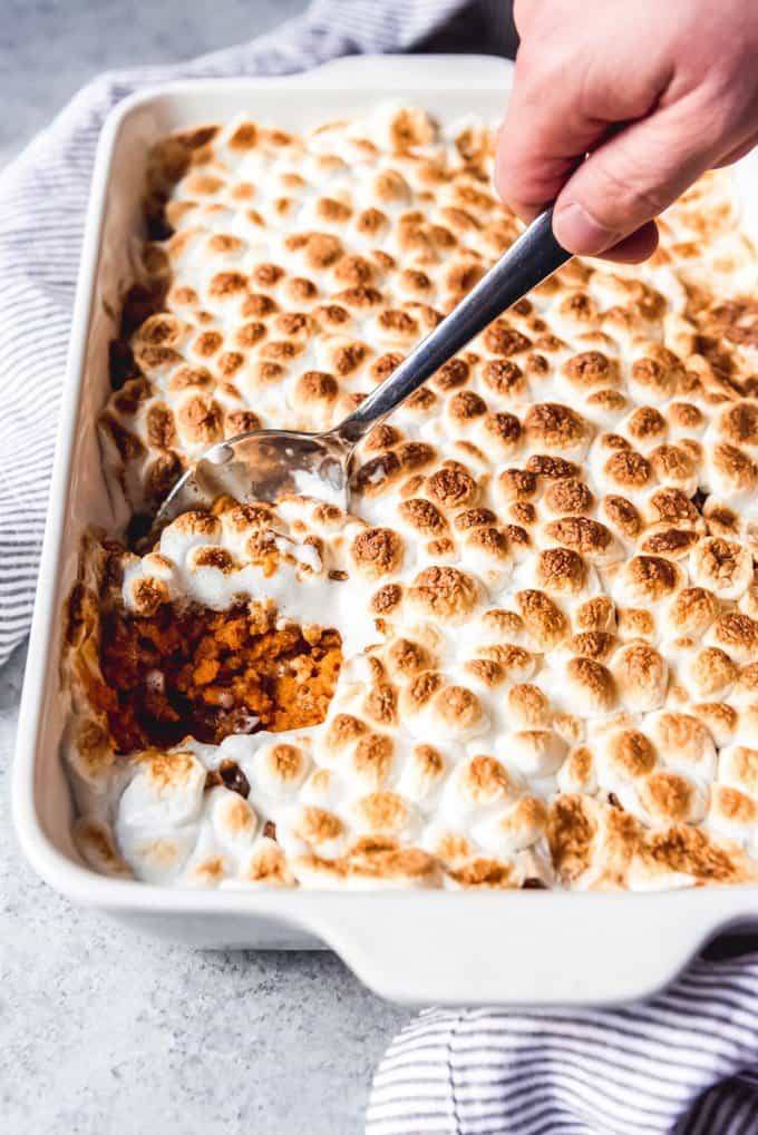 An image of a scoop of brown sugar and cinnamon sweet potato casserole with marshmallows and pecans for Thanksgiving dinner.