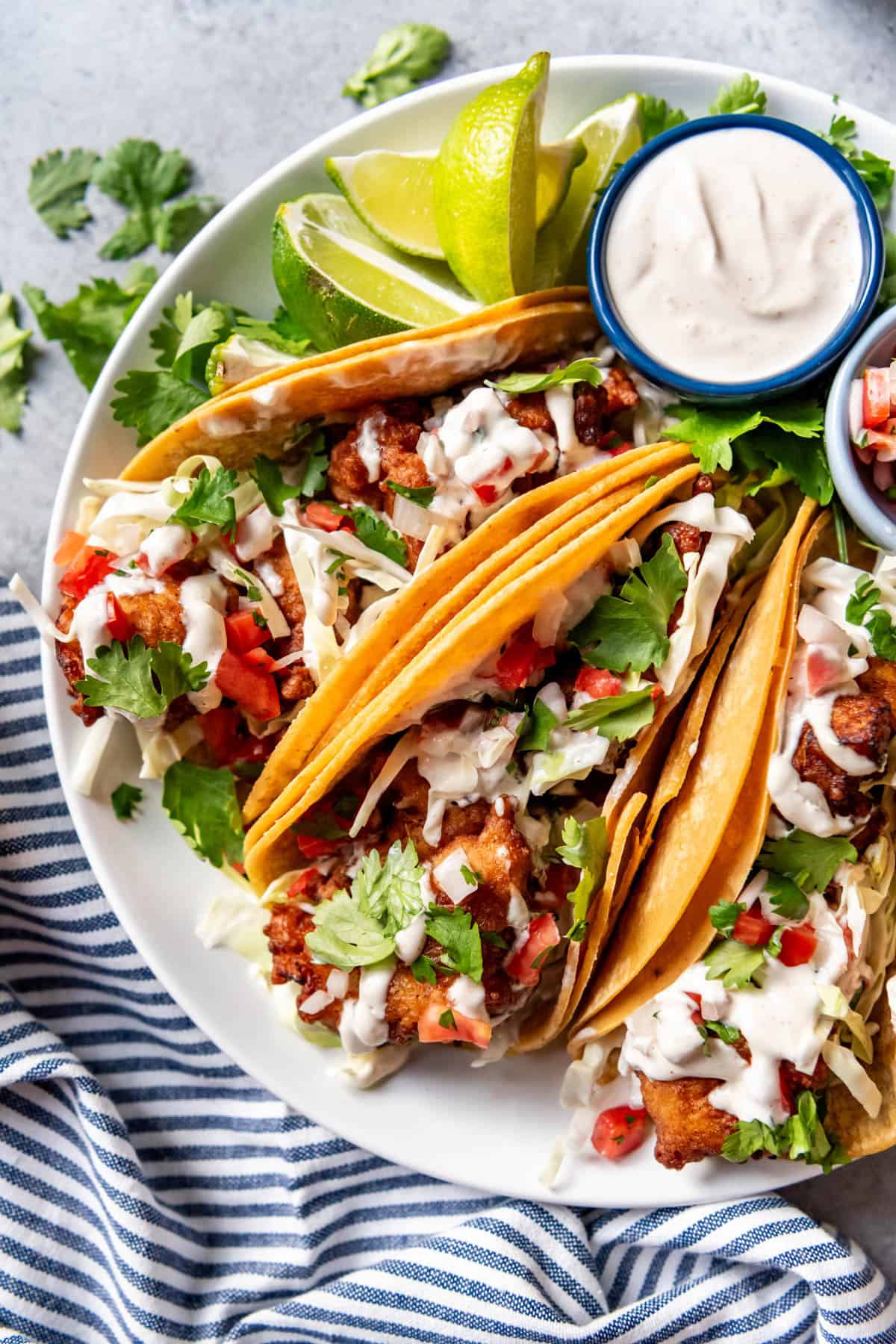 An image of a platter of the the ultimate Mexican street food - fish tacos made Baja style, battered and fried with a creamy fish taco sauce, cabbage, cilantro, and pico de gallo!
