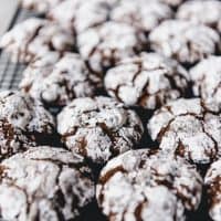 powdered sugar covered double chocolate crinkle cookies on a wire cooling rack