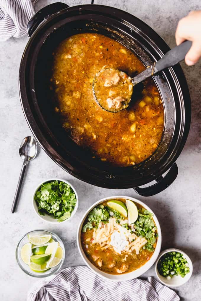 scooping pork green chili out of a slow cooker
