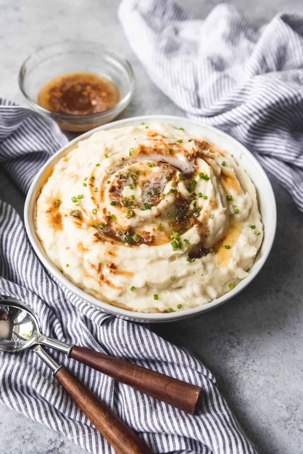A big bowl of creamy mashed potatoes for Thanksgiving dinner with browned butter drizzled over top.