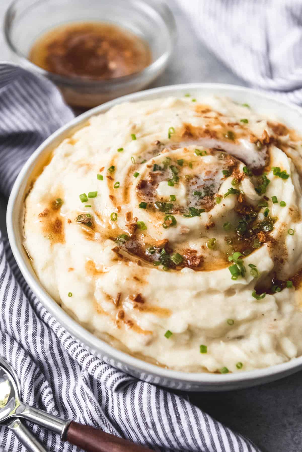 Garlic brown butter mashed potatoes in a bowl with garnish.