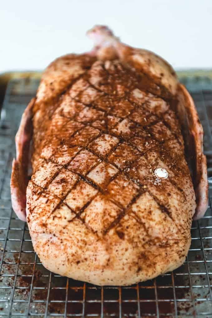 An image of a scored duck breast on a whole duck, rubbed with a spice rub for roasting in the oven.