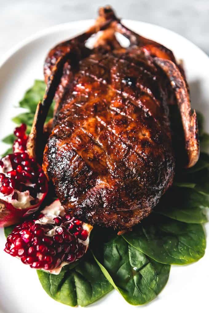 honey roasted duck on a bed of spinach with a broken open pomegrante to the side