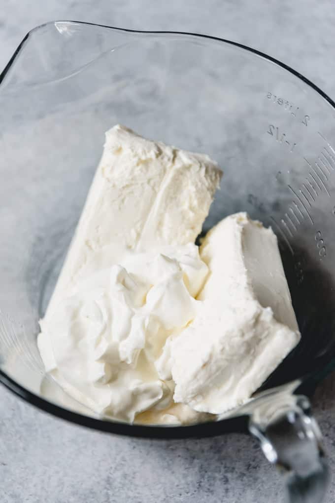 An image of cream cheese, mayonnaise, and sour cream in a bowl for making a creamy jalapeno popper dip.