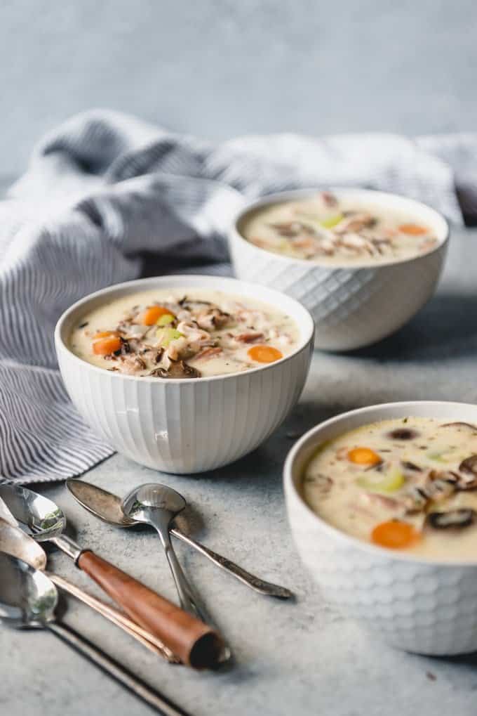 An image of bowls of creamy wild rice soup with leftover smoked turkey and vegetables in bowls.