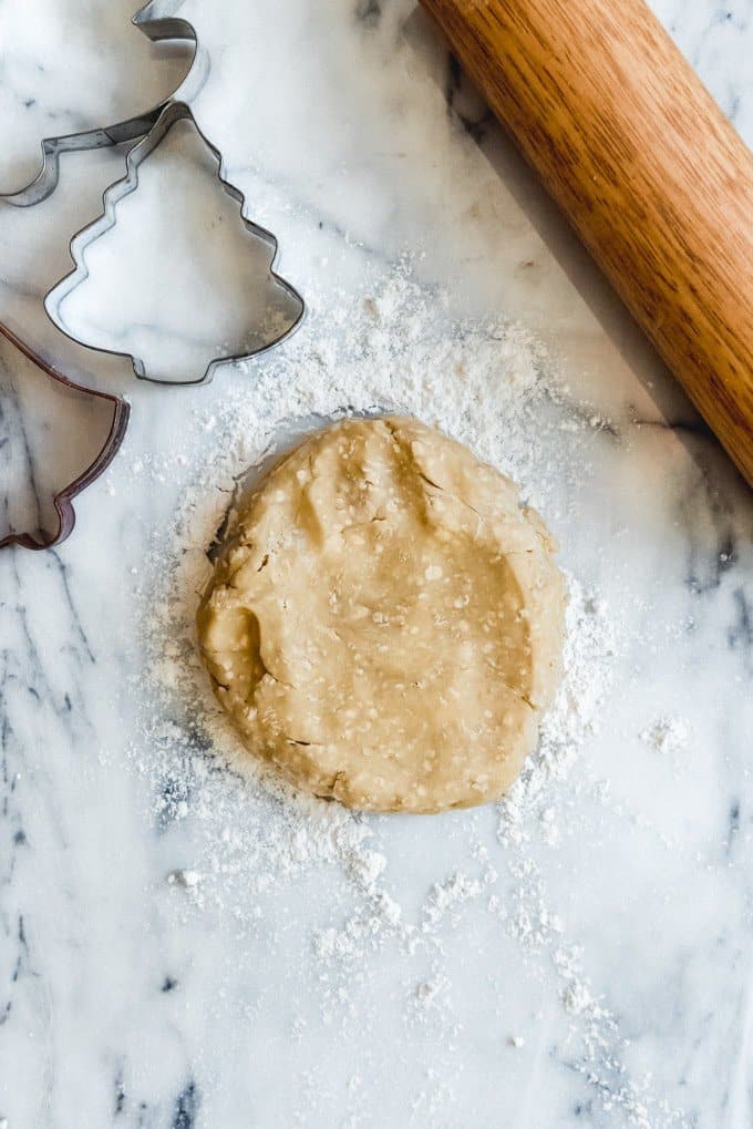 An image of chilled oatmeal sugar cookie dough on a floured surface, ready to be rolled out and cut into Christmas shapes.