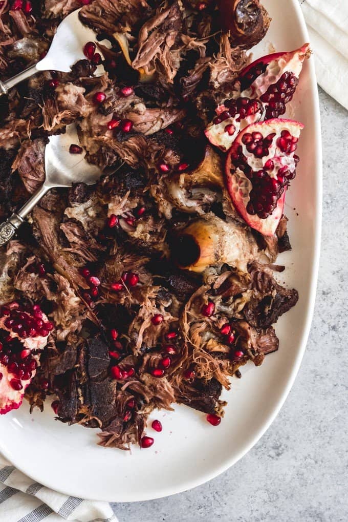 An image of a platter of shredded lamb shoulder that has been slow roasted and pulled apart, then garnished with pomegranate seeds.
