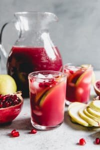 Pomegranate in a Pear Tree Punch in glasses and in a pitcher with fresh fruit scattered around