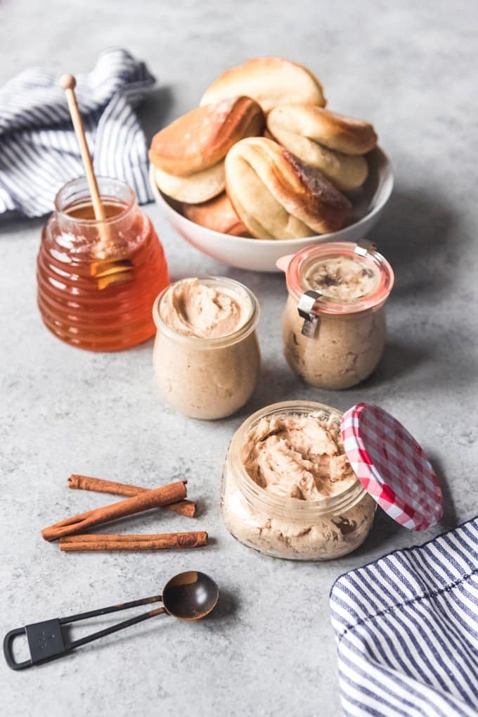 An image of small glass jars of a whipped cinnamon honey butter recipe for an easy edible gift for the holidays.