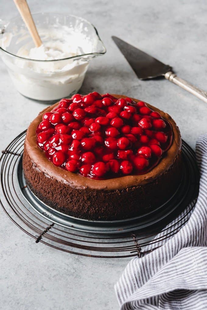 An image of a chocolate cheesecake with cherries on top.