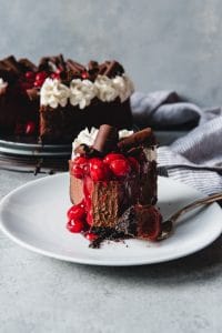 a slice of chocolate cherry cheesecake with a bite taken out of it.