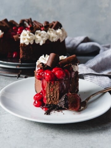 a slice of chocolate cherry cheesecake with a bite taken out of it.