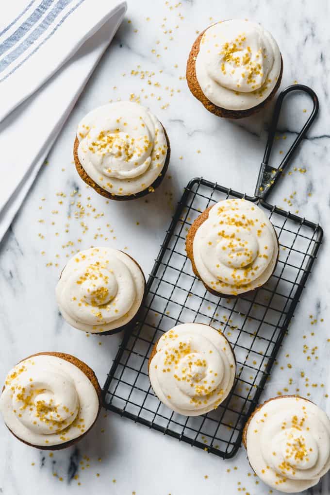 An image of gingerbread Christmas cupcakes frosted with swirls of eggnog buttercream frosting and sprinkled with gold star sprinkles.