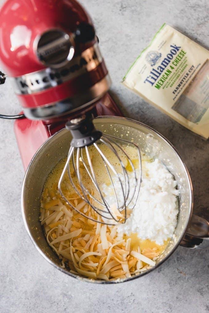 An image of a stand mixer with beaten eggs, cottage cheese, and shredded Mexican blend cheese for an easy Mexican breakfast casserole.