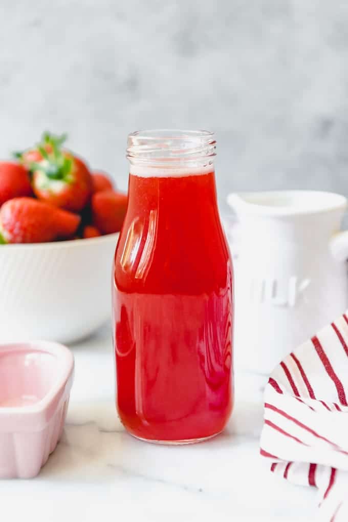 An image of a jar of homemade strawberry syrup from scratch to be used for flavoring drinks.