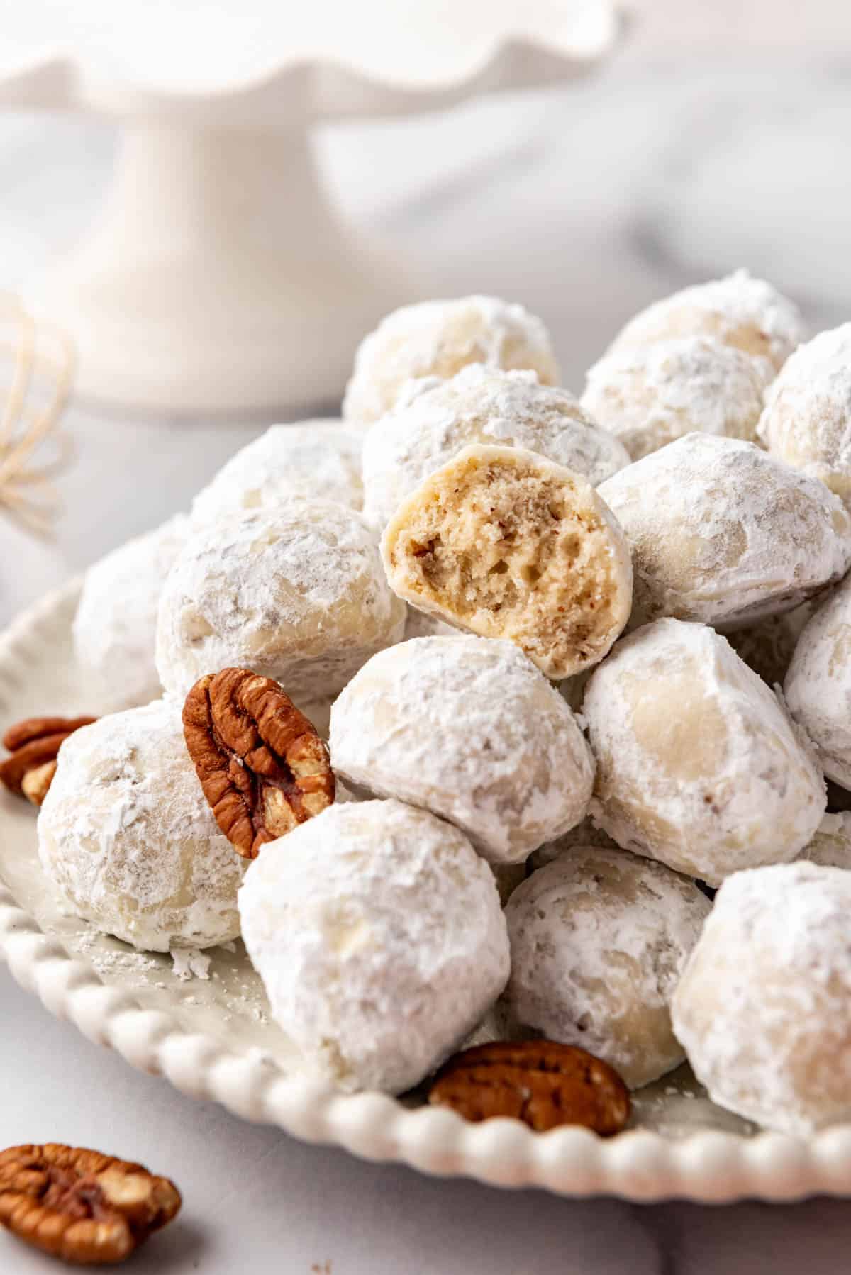 A close image of Mexican wedding cookies with a bite taken out of one of them.