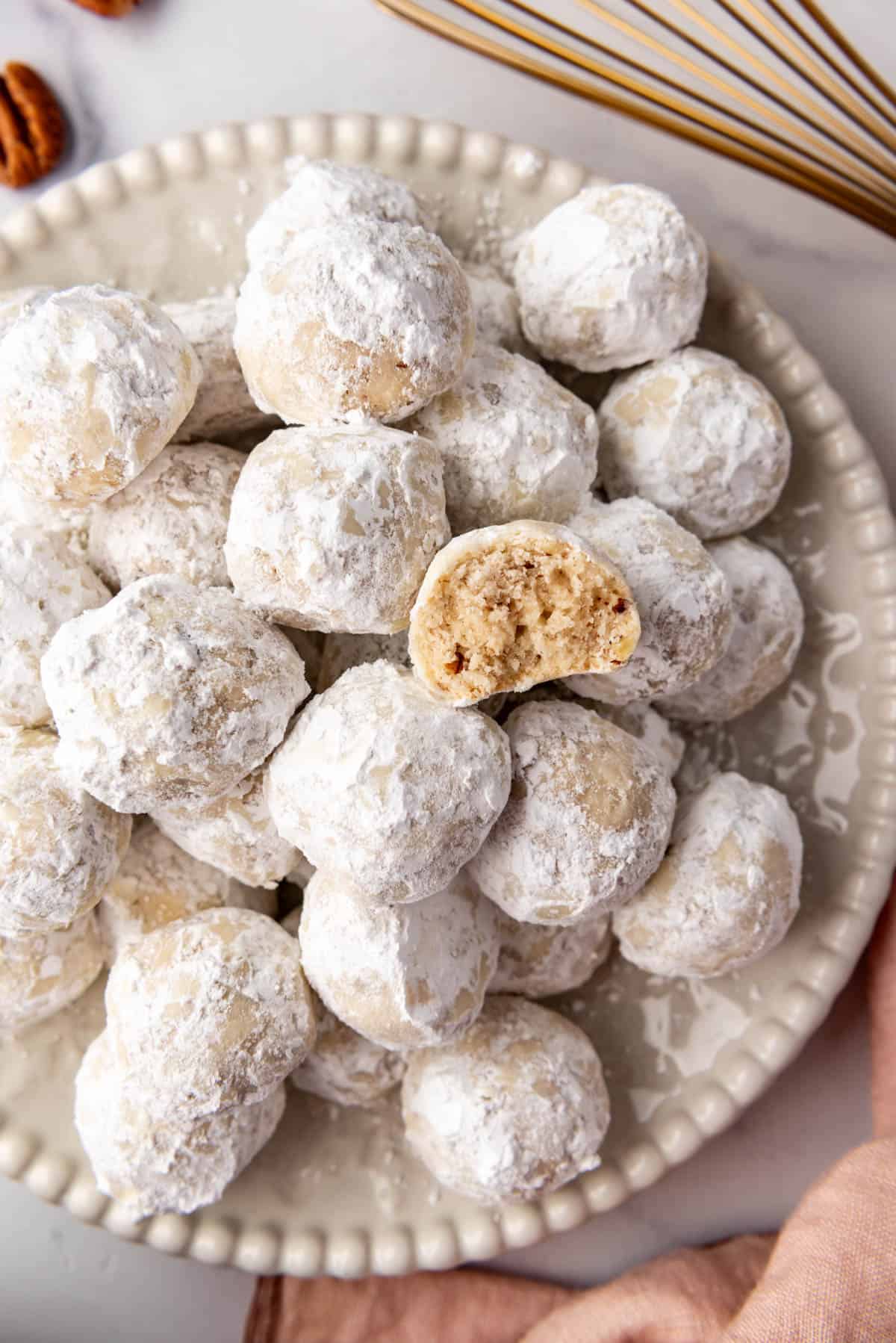 An overhead image of a Mexican wedding cookie with a bite taken out of it on top of more cookies.