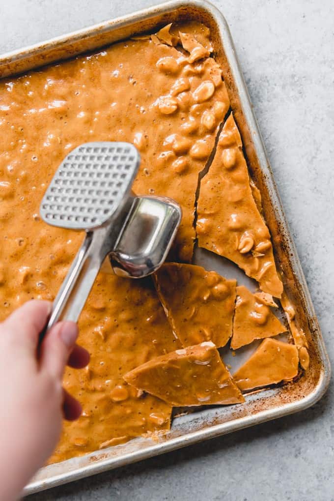An image of homemade peanut brittle being broken up with a mallet.